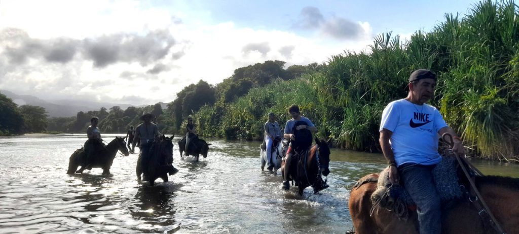 Men on horseback crossing a river, horseback riding on Los Naranjos beach